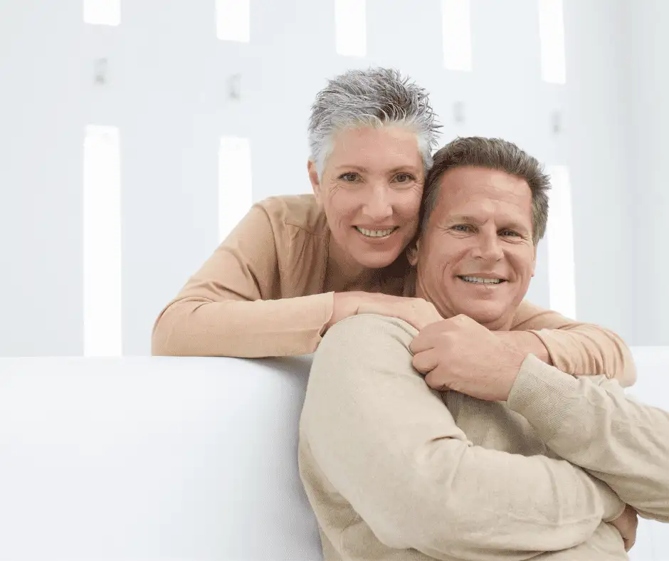 A content mature couple embracing, with smiles that suggest satisfaction with their dental care including affordable dentures and wisdom teeth extractions.